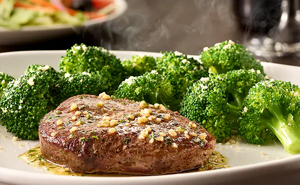 Juicy 6 oz sirloin steak grilled to perfection served with herbs and butter