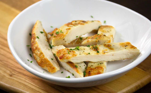 Side of grilled chicken breast served hot with herbs and seasoning