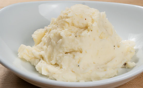 Creamy side of mashed potatoes served with butter and herbs