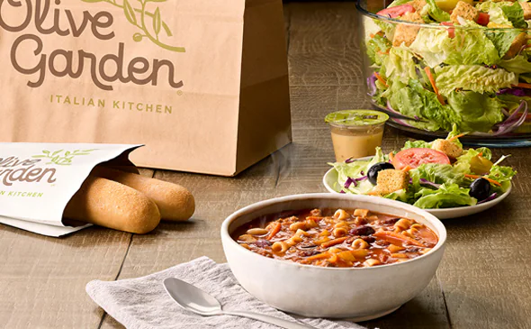 Fresh soup, garden salad, and warm breadsticks served together as a meal