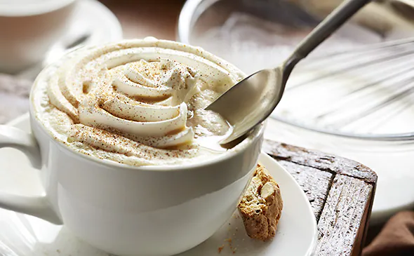 Hot cappuccino coffee topped with frothy milk foam served in a cup