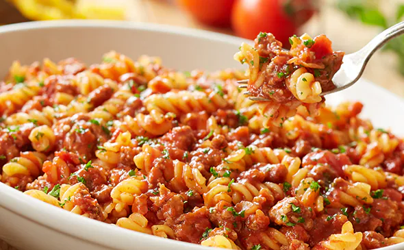 Rotini pasta with meat sauce served hot and topped with parmesan cheese