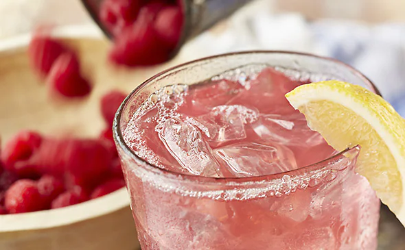 Refreshing raspberry lemonade served cold with ice and fresh raspberries