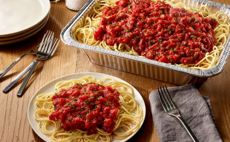 Olive Garden Spaghetti with Marinara Sauce Family Meal featuring spaghetti pasta topped with fresh tomato marinara sauce and garnished with Italian herbs and parmesan cheese, served in a catering pan.