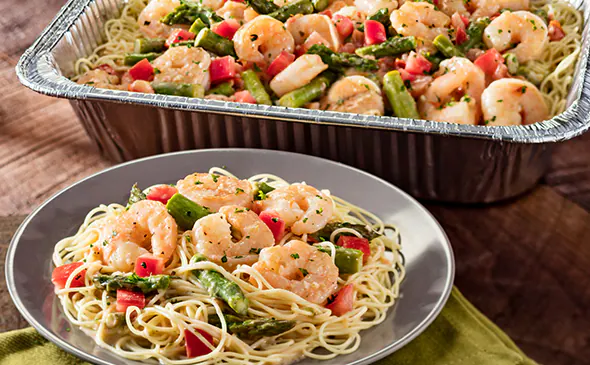 Olive Garden Shrimp Scampi Family Meal featuring shrimp, angel-hair pasta, asparagus, and tomatoes in creamy garlic sauce.